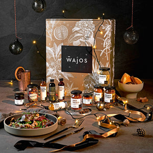 Wajos Gourmet & Gewürz Adventskalender in goldenem Karton mit Produkten und weihnachtlicher Deko