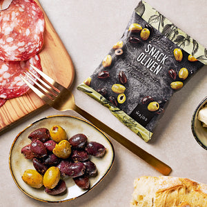 Snack Oliven Kalamata + Grün gemischt mit Kräutern dargestellt in Servierschale