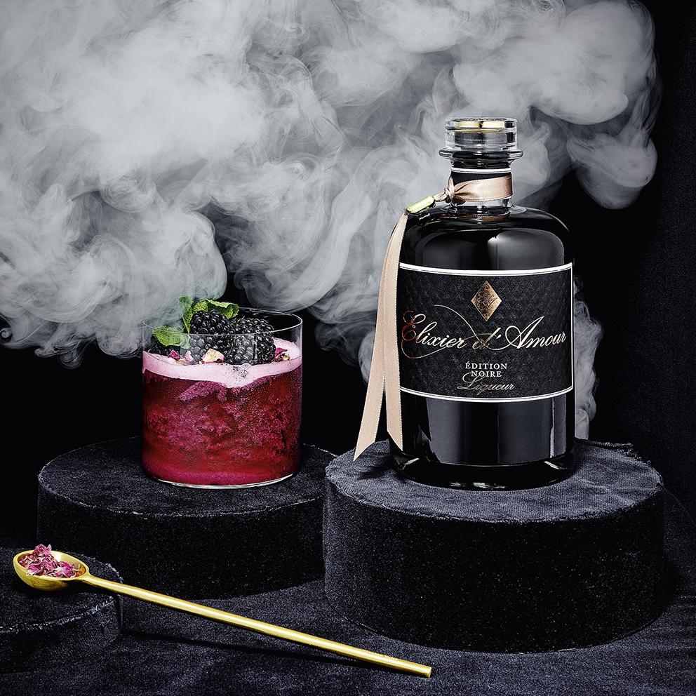 Elixier d'Amour Edition Noire dargestellt mit Cocktail
